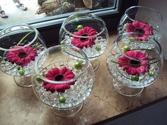 four clear vases with flowers in them on a counter