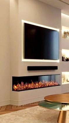 a living room with a large television mounted on the wall and a fire place in front of it