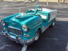 an old green car parked in a parking lot