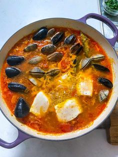 a pan filled with seafood and mussels on top of a table