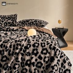 a leopard print comforter set on a bed with two champagne glasses in the corner