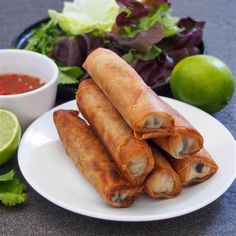 some food that is on a white plate next to a bowl of sauce and lettuce