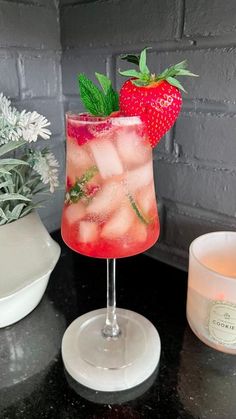 a drink with strawberries in it sitting on top of a table next to a potted plant