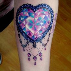 a colorful heart tattoo on the leg with beads and jewels around it's edges