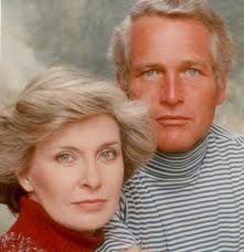 an older man and woman are posing for a photo together, one is wearing a turtle neck sweater