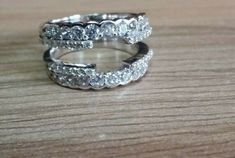 two wedding rings sitting on top of a wooden table next to each other with diamonds in them