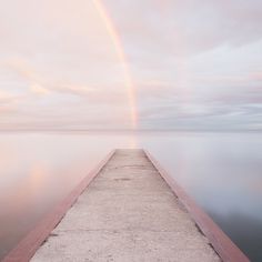 a long dock with a rainbow in the background