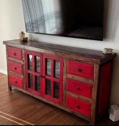 an entertainment center with red drawers and a flat screen tv mounted on the wall