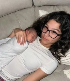 a woman is laying on a couch holding a baby