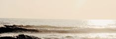 a person riding a surfboard on top of a wave in the ocean at sunset