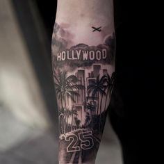 a man with a tattoo on his arm that says hollywood and palm trees in the background