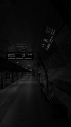 a black and white photo of a train station with benches in the dark, looking like an empty subway