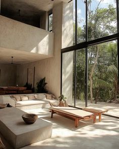 a living room filled with lots of furniture next to large glass windows on the wall