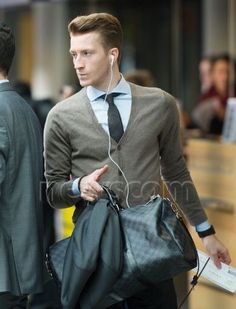 a man in a suit and tie walking down the street with headphones on his ears