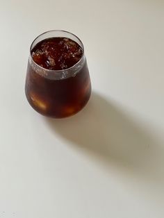 a glass filled with liquid sitting on top of a white table next to a banana