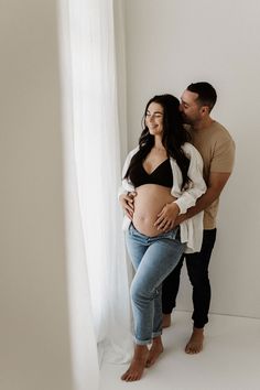 Intimate photograph of couple embracing each other during maternity shoot. Photographed in Catherine Smith Photography's natural light, timeless white studio in Hamilton, New Zealand. Jean And White Maternity Shoot, Maternity Photography White Shirt And Jeans, Jean Maternity Shoot Couple, Maternity Pictures Jeans And White Shirt, Casual Maternity Shoot, Couples Maternity Photoshoot, Indoor Maternity Photos, Studio Maternity Shoot, Maternity Couple