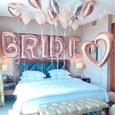 a bed with balloons that say bridal and heart shaped balloons hanging from the ceiling