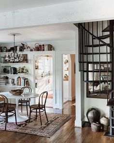 a dining room table and chairs in front of a spiral stair case with bookshelves