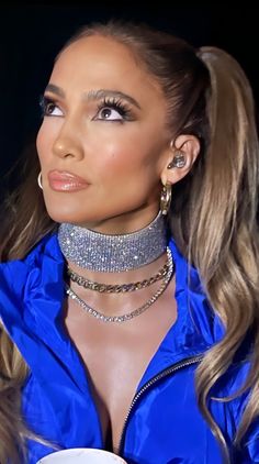 a woman wearing a blue shirt and silver choker