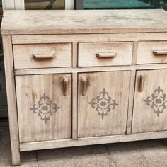 an old wooden cabinet with metal handles and knobs on the doors is sitting in front of a window