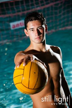 a shirtless man holding a yellow ball in the water