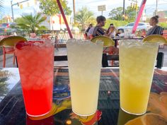 three different colored drinks sitting on top of a table