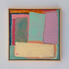 an abstract painting with different colors and shapes in a wooden frame hanging on the wall