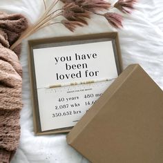 an open box with a sign on it sitting next to some dried plants and other items