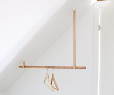 two wooden clothes hangers hanging from the side of a white wall in a bedroom