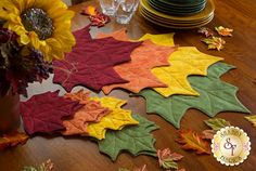 the table is set with autumn leaves and place settings