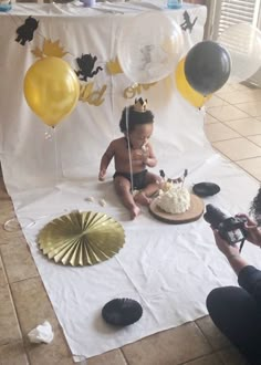 a baby is sitting on the floor in front of a cake