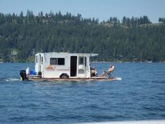 a small boat with two people on it in the middle of water near some trees