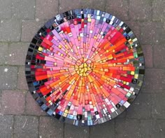 a colorful mosaic table sitting on top of a stone floor next to a brick sidewalk