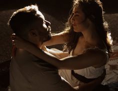 a man and woman sitting next to each other on a bed in front of a wall