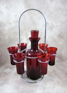 a set of red glass vases and cups on a metal stand with a handle