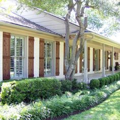 a white house with red shutters and trees