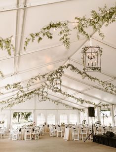 the inside of a white tent with tables and chairs set up for a wedding reception