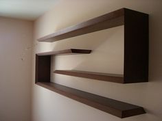 three wooden shelves mounted to the wall in a room with no one around them or someone else