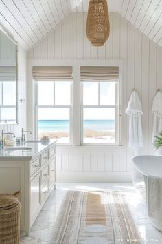 a white bathroom with a large window overlooking the beach and ocean is featured in this image