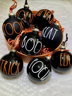 black and orange ornaments with the word trick written on them are in a round bowl