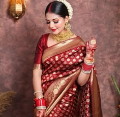 a woman in a red and gold sari holding her hand up to the side