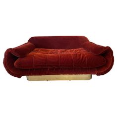 a red couch sitting on top of a wooden stand