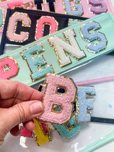 someone is holding up some type of letter brooch in front of their name tags