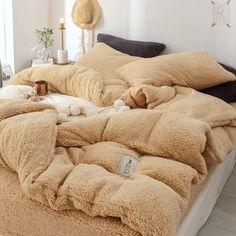 an unmade bed with fluffy blankets and pillows