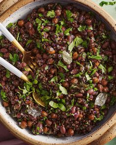 a bowl filled with beans and greens on top of a table