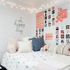 a bed with lots of pillows and pictures on the wall next to it in a bedroom