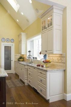 a large kitchen with white cabinets and marble counter tops