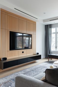 a living room with a couch, television and large window in the back ground area