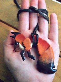 a hand holding a clay animal on a string