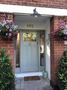 a blue front door with flowers hanging from it's sides and the number 1012